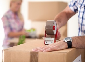 Close up of male hand packing cardboard box, concept moving hous